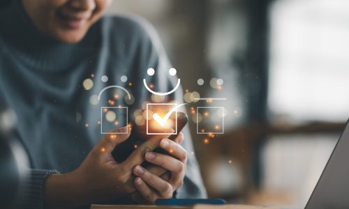 Customer service evaluation concept. smiling Asian female Is using a smartphone And she is pressing face emoticon smile in satisfaction on virtual touch screen.